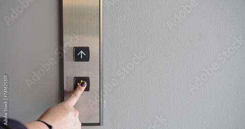 A person is pointing at a button on an elevator photo