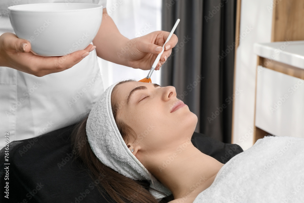 Cosmetologist with brush applying cosmetic product to client`s face in clinic, closeup Cosmetologist with brush applying cosmetic product to client`s face in clinic, closeup