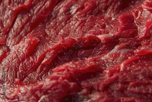 A close-up texture of red raw beef meat, highlighting the marbling and fibrous structure of the muscle