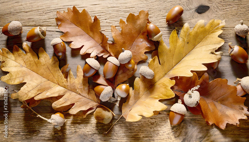 Scattered autumn leaves and acorns on a wooden table.
