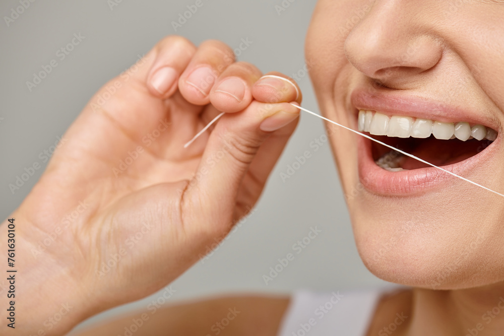excited cropped woman holding dental floss and smiling on grey background, promoting oral hygiene excited cropped woman holding dental floss and smiling on grey background, promoting oral hygiene
