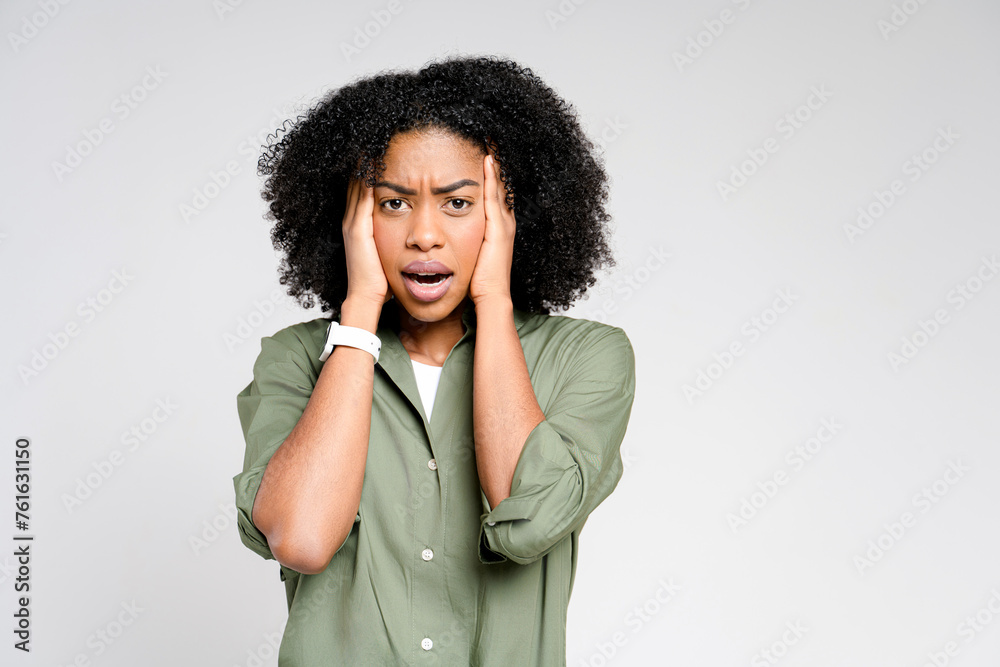 With an expression of concern, this African-American woman holds her head in her hands, her furrowed brow and pensive look conveying a sense of worry or deep thought on a neutral background With an expression of concern, this African-American woman holds her head in her hands, her furrowed brow and pensive look conveying a sense of worry or deep thought on a neutral background