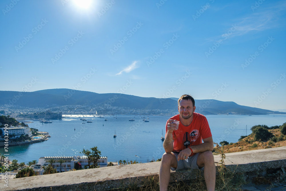 relaxation on the coastline, young man enjoying beautiful travel.  happy young man sitting near the sea