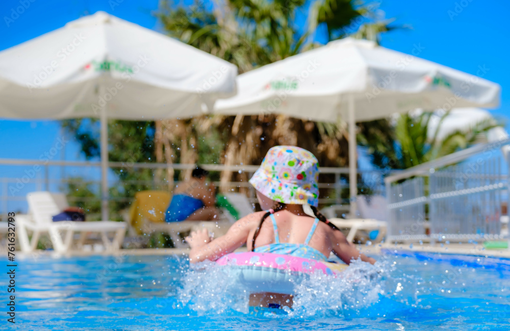 Child in swimming pool floating on toy ring. Kids swim. Colorful rainbow float for young kids. Little boy having fun on family summer vacation in tropical resort. Beach and water toys. Sun protection