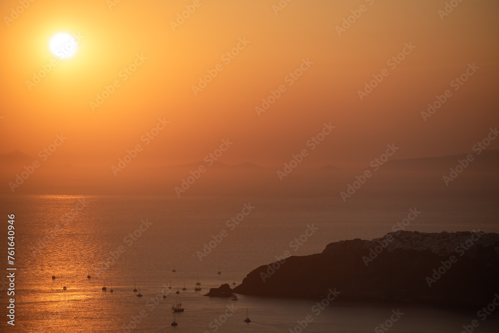 A shot of sunset over caldera in Santorini. Sailboats and catamarans on the water