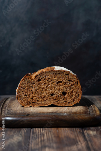 half rye bread on a wooden cutting board, vertical © cook_inspire