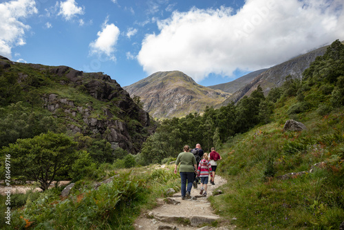 A family walks on the Ben Nevis mountain path leading to Steall waterfall. Scottish highlands on a summer day