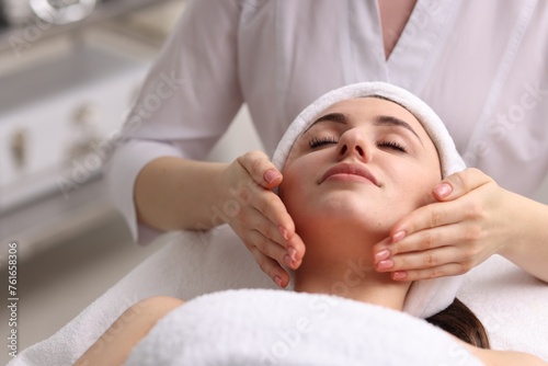 Cosmetologist making face massage to client in clinic, closeup