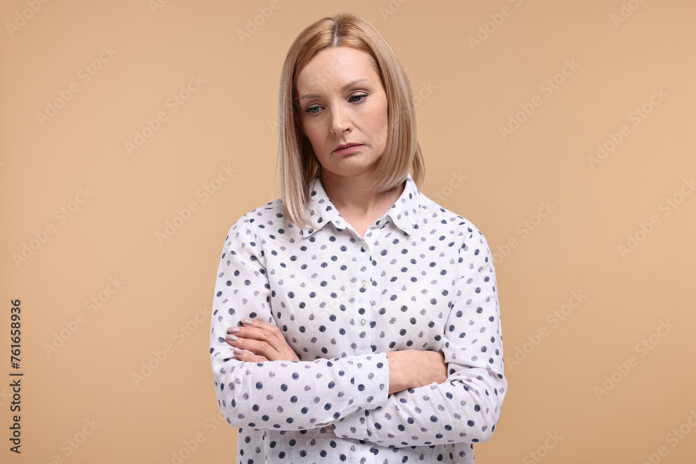 Obraz premium Portrait of sad woman with crossed arms on beige background