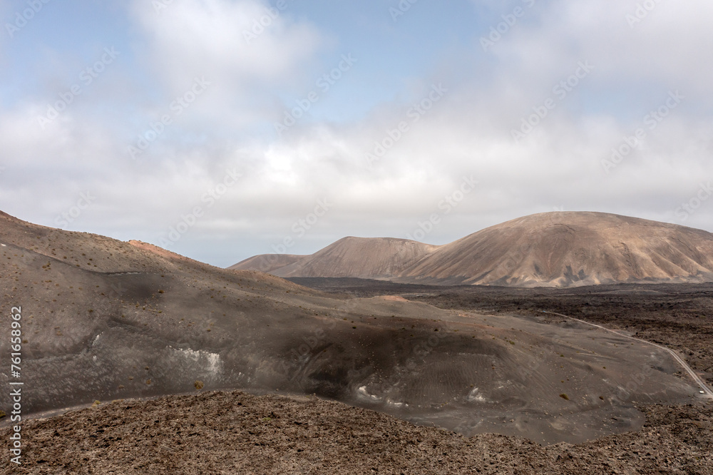 View over multiple small volcanoes among vast lava fields in Timanfaya National park, Lanzarote, Canary islands View over multiple small volcanoes among vast lava fields in Timanfaya National park, Lanzarote, Canary islands
