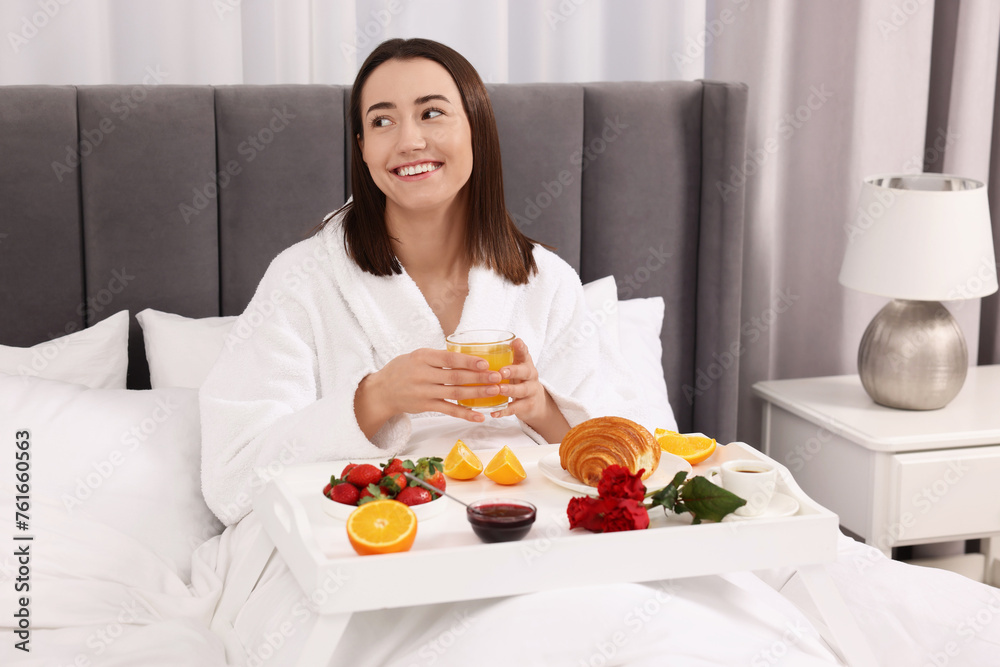 Smiling woman having breakfast in bed at home
