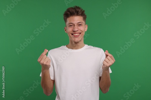 Happy man showing money gesture on green background