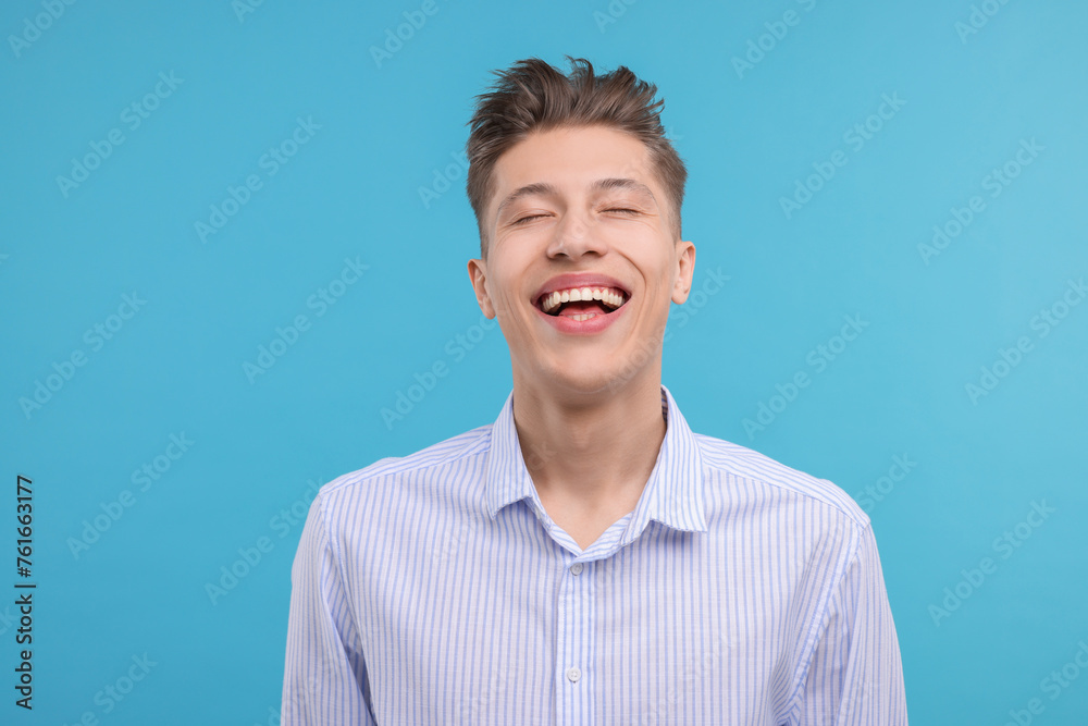 Young man laughing on light blue background Young man laughing on light blue background