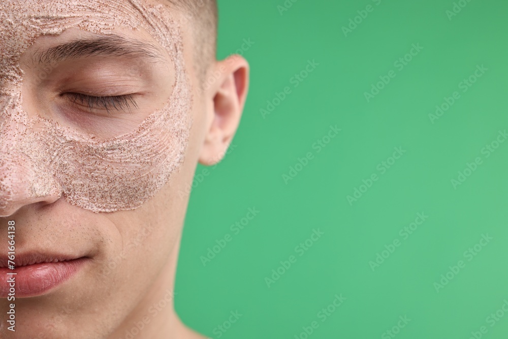 Handsome man with facial mask on his face against green background, closeup. Space for text