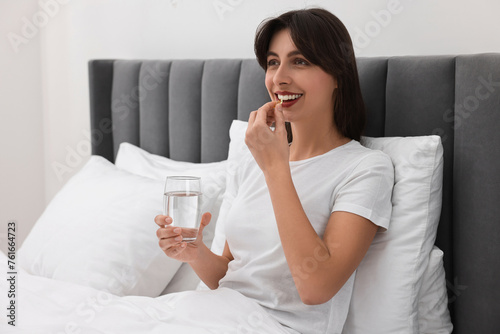 Beautiful woman taking vitamin pill at home