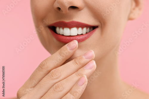 Woman with beautiful lips smiling on pink background, closeup