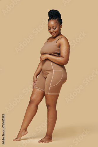 Curvy smiling Black woman wearing high waisted shaper shorts and sports bra