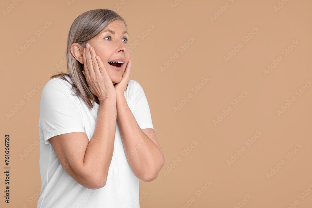 Portrait of surprised senior woman on beige background, space for text Portrait of surprised senior woman on beige background, space for text