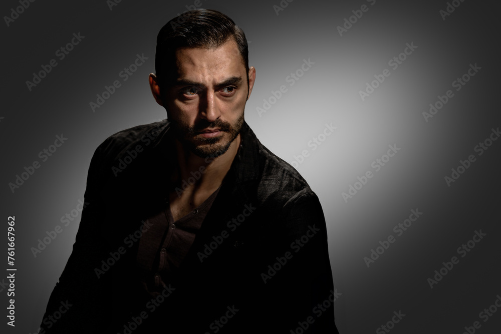 Fashion photo of confident serious handsome man with beard, Serious young man with a dark background, showcasing a striking, rugged portrait