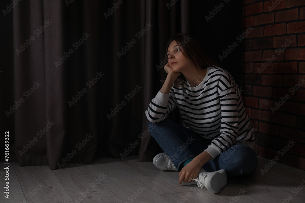 Sad young woman sitting on floor indoors, space for text Sad young woman sitting on floor indoors, space for text
