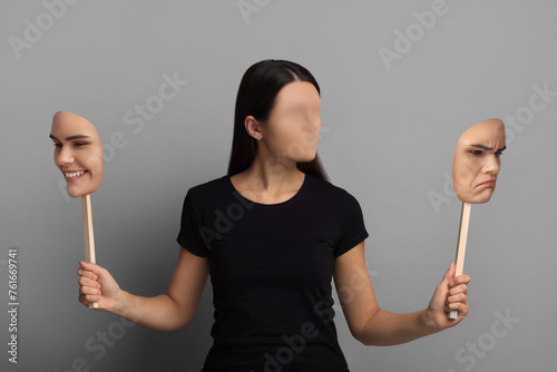 Faceless woman holding her face masks showing different emotions on grey background. Personality crisis.