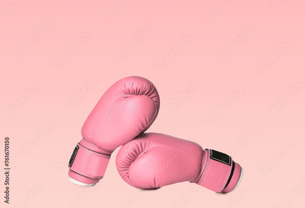 Breast cancer. Pair of pink boxing gloves on color background