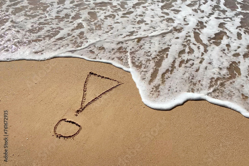 Exclamation mark writing on beach sand on blue water waves background. Top view.