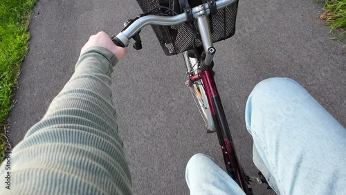 POV Young woman riding her bike on a cycling path in a city at sunset