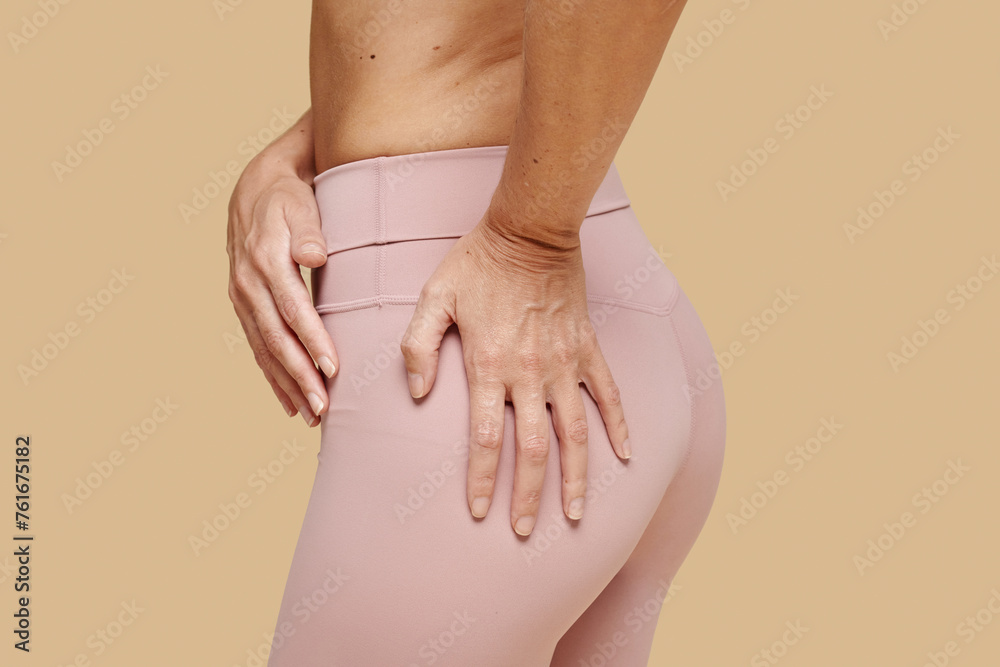 Fit woman touching her tight butt in pink leggings