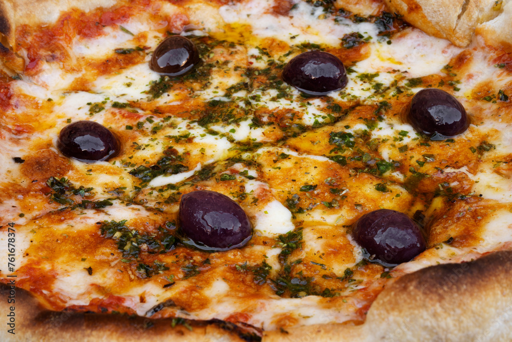 Traditional Italian pizza background. Top view of a mozzarella cheese pizza with tomato sauce, black olives and fresh oregano Traditional Italian pizza background. Top view of a mozzarella cheese pizza with tomato sauce, black olives and fresh oregano