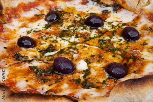 Traditional Italian pizza background. Top view of a mozzarella cheese pizza with tomato sauce  black olives and fresh oregano