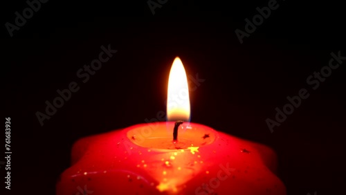 candele rosse su sfondo nero accese con fiamme oro e gialle che evocano un'atmosfera incantevole suggestiva religiosa e natalizia quasi mistica photo