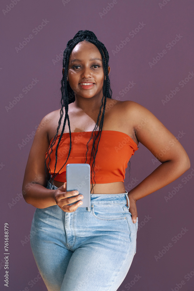 Fototapeta premium Portrait of smiling curvy Black woman posing with smartphone