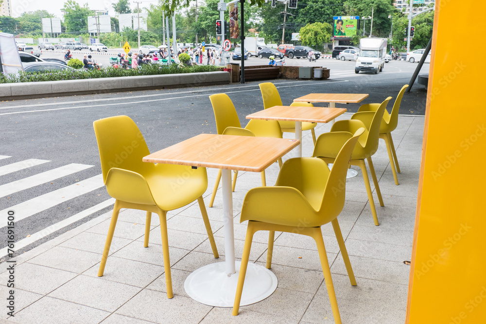 Yellow steel chairs and tables near street in city, empty with nobody using the area,restaurant or cafe.