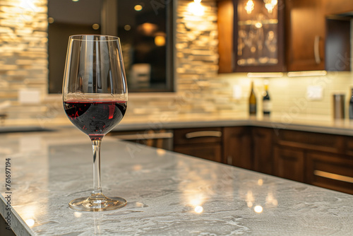 a glass of red wine on the bar counter in front view with beautiful lighting and a background showing a modern interior design with kitchen cabinets made from natural stone