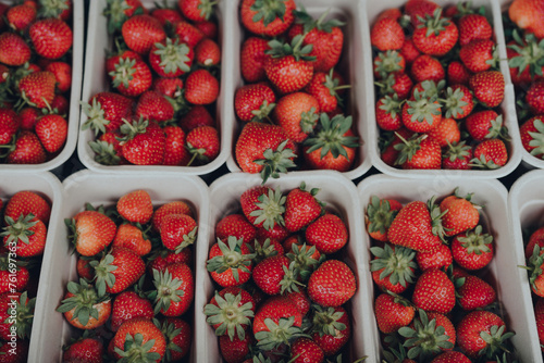 Top view of fresh strawberries on sale, portioned in recycled carton boxes. photo