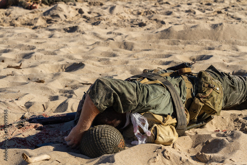 Historical reconstruction. Injured or dead World War II infantry soldier on the beach. View from the back. Hel, Poland