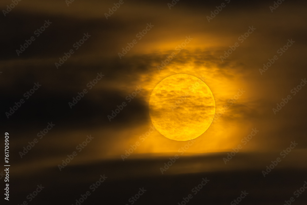 Full moon in the night sky, covered with clouds.