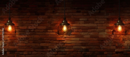 Three lights dangle from the ceiling, illuminating the brown hardwood flooring against the brick wall. The circle of light breaks through the darkness
