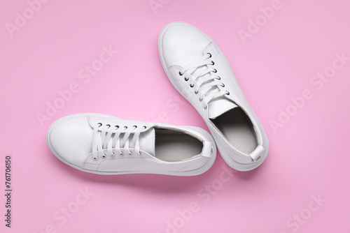 Pair of stylish white sneakers on pink background, top view