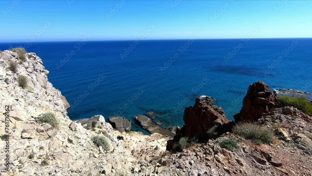 Rocky coast of the Mediterranean sea from the top of a cliff in summer day with blue sky, in Almeria, Andalusia, Spain. Point Of View (POV), subjective view Rocky coast of the Mediterranean sea from the top of a cliff in summer day with blue sky, in Almeria, Andalusia, Spain. Point Of View (POV), subjective view