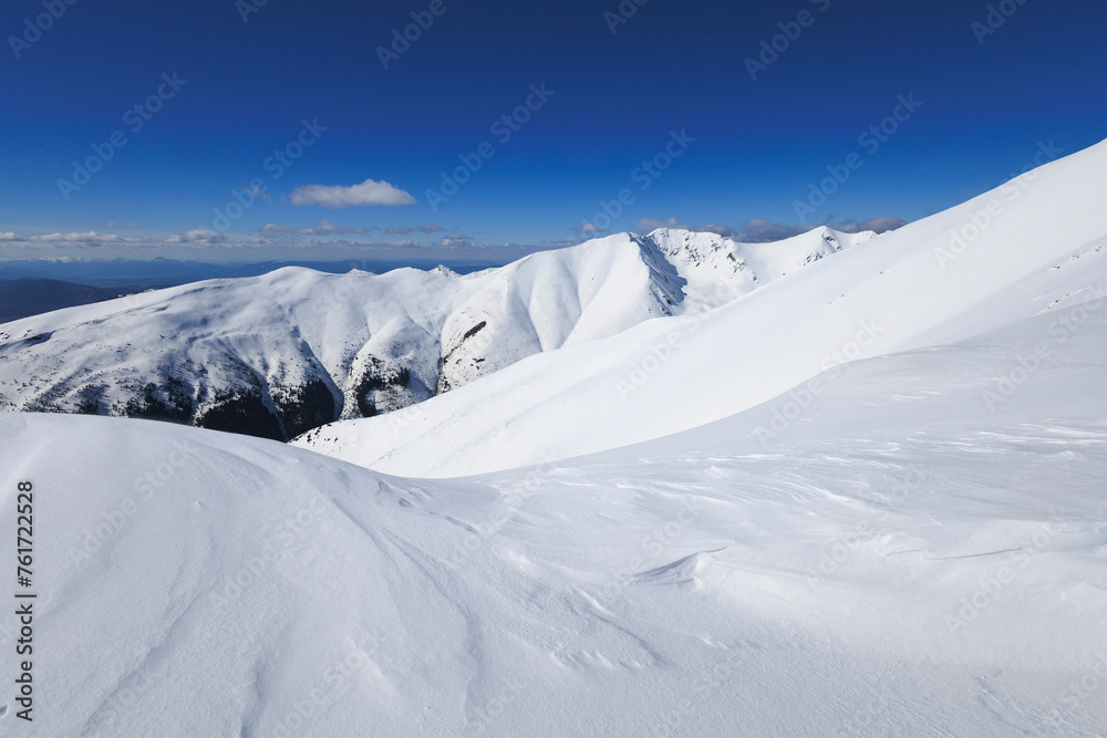 View from Baranec, Western Tatras, Slovakia. Beautiful winter landscape of mountains is covered by snow in wintertime. Sunny weather with clear blue sky and white snow. Wide angle with soft corners.