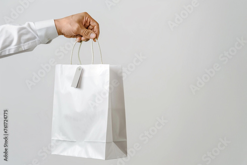 Close-up of hand holding shopping bag against a crisp white isolated solid background, highlighting the sleek and clean design,