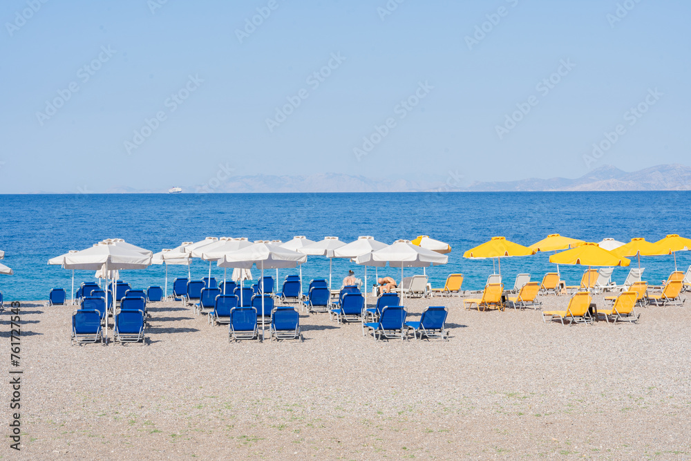 Beautiful view of a beach on the island of Rhodes full of brightly colored umbrellas and hammocks without people at the beginning of summer