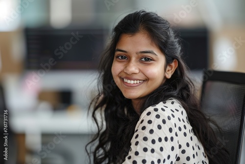 Portrait of a smiling Indian woman in a polka dot shirt looking at the office © Nld