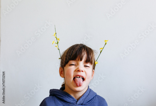 portrait of smiling little girl with flowers on top of the head showing her tongue photo