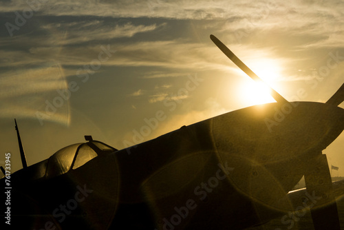 The sun rises behind a Spitfire at an airshow.