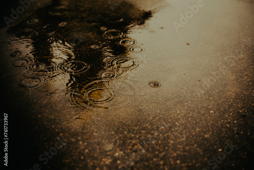 On a dark and rainy evening, the raindrops fell into a puddle in the city streets. The weather was bad.
