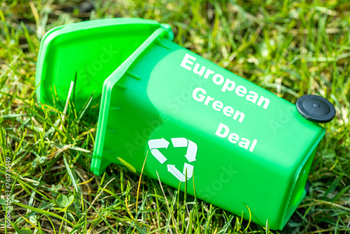 green garbage bin lying in the grass with the text European Green Deal, Environmental concept, Changes in the Green Deal, Farmers' protests, ecological project