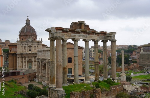 Ruins of the temple of Saturn, the arch of Septimius Severus and the Curia Julia senate house behind, in the Roman forum, in Rome, Italy
